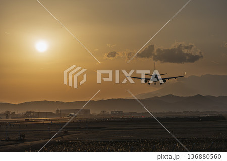 夕暮れの仙台空港　夕日と着陸中の飛行機　宮城県名取市 136880560