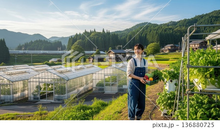 収穫した野菜を持つ笑顔の若い女性農家と日本の美しい里山の風景 収穫した野菜を持つ笑顔の若い女性農家と日本の美しい里山の風景 136880725