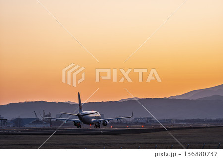 夕暮れの仙台空港　夕日と離陸中の飛行機　宮城県名取市 136880737