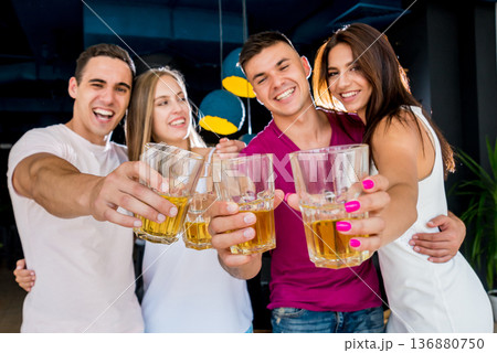 Cheerful friends in the pub. Drinking beer, talking, having fun. 136880750
