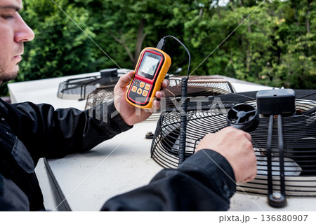 Technician use hand-held anemometer measuring air flowing measurement Technician use hand-held anemometer measuring air flowing measurement 136880907