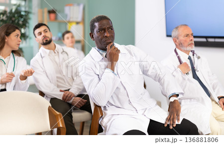 African man doctor student at courses meeting listens to teacher and look at speaker 136881806