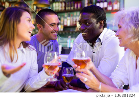Cheerful international friends different ages enjoying pinchos and beer in the evening pub 136881824