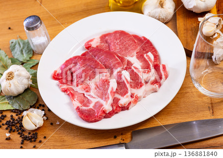 Raw pork neck on the kitchen table along with other ingredients for making delicious lunch or dinner 136881840