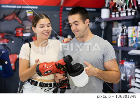 Couple talking while choosing paint sprayer in hardware store 136881849