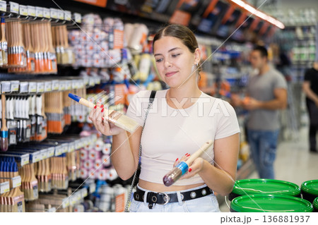 Woman choose brush made for painting wooden surfaces and selects desired option 136881937
