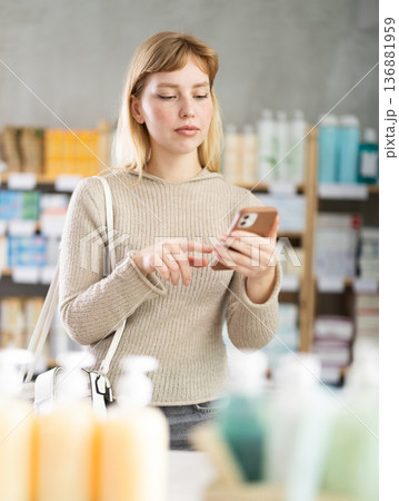 Young woman with phone choosing medicines and hygiene products 136881959