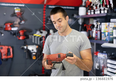 Focused man choosing electric drill in local hardware store Focused man choosing electric drill in local hardware store 136881976