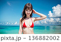 夏空のビーチでビキニの水着を着た笑顔の若い女性 136882002