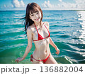 夏空のビーチでビキニの水着を着た笑顔の若い女性 136882004