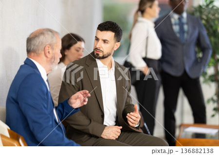 Young and elderly men talking while waiting in job interview queue 136882138