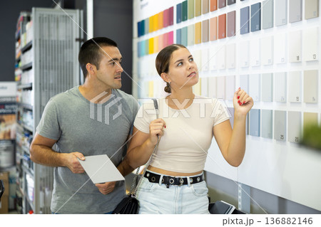 Couple choosing paint colors on swatch stand in construction hypermarket 136882146