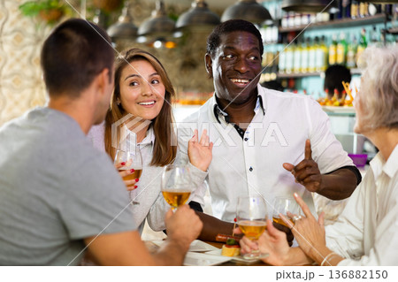 Happy men and women friends enjoy and fun holiday party with glasses of beer. Focus on african american man 136882150