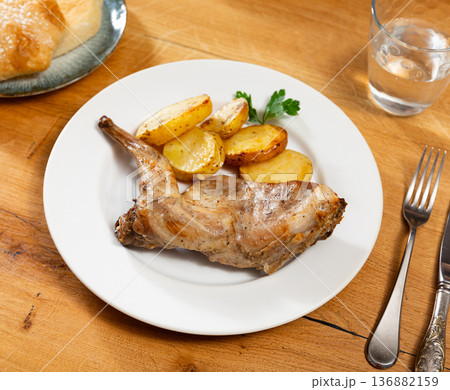 Lunch is served on plate - pieces of young rabbit cooked with segments of potato. Close-up Lunch is served on plate - pieces of young rabbit cooked with segments of potato. Close-up 136882159
