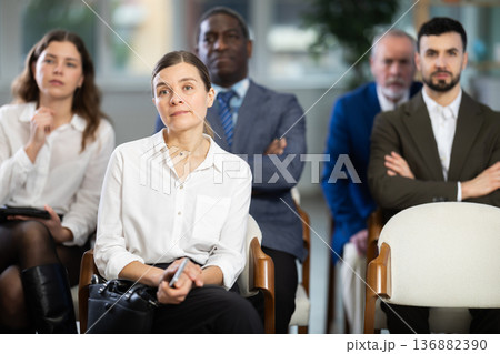 Adult woman listens to presentation in conference room 136882390