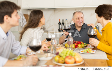 Father and mother together with adult children talking at dinner table at home Father and mother together with adult children talking at dinner table at home 136882408