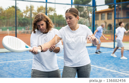 Paddle tennis instructor giving lessons to girl 136882456