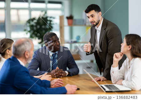 Man stands in front of business colleagues, tells report 136882483