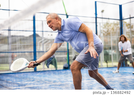 Emotional mature man playing paddle tennis outdoors Emotional mature man playing paddle tennis outdoors 136882492