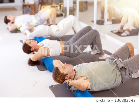 Young and adults maintaining physical health practicing pilates with with rolled mats 136882548