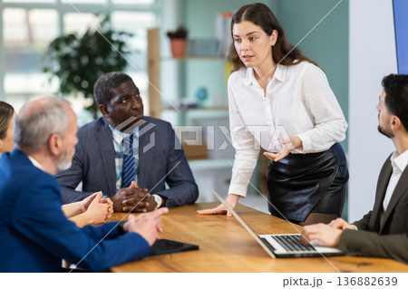 Girl stands in front of business colleagues, tells report Girl stands in front of business colleagues, tells report 136882639