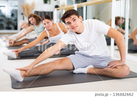 Portrait of flexible women and men practice yoga in modern studio. Portrait of flexible women and men practice yoga in modern studio. 136882662