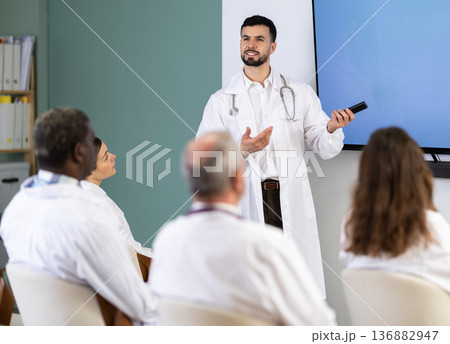 Young male doctor presenting with remote control in meeting room 136882947