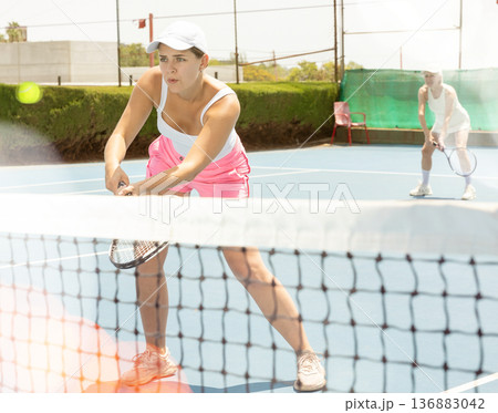 Young woman playing tennis with her teammate in court 136883042