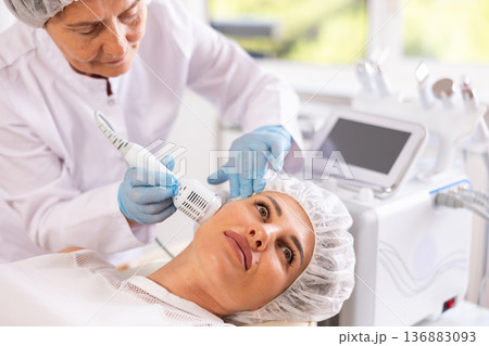 Young woman undergoing hardware facial treatment using cold hammer Young woman undergoing hardware facial treatment using cold hammer 136883093