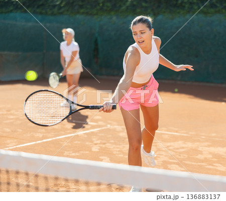 Young woman playing tennis with older woman 136883137