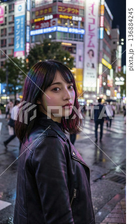 煌びやかな夜の繁華街でレザージャケットを着て振り返る女性 136884245