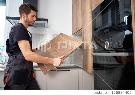 Man installing wooden kitchen cabinet door panel Man installing wooden kitchen cabinet door panel 136884403