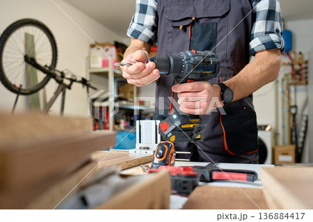 Carpenter Holding Cordless Drill in Woodworking Workshop Carpenter Holding Cordless Drill in Woodworking Workshop 136884417