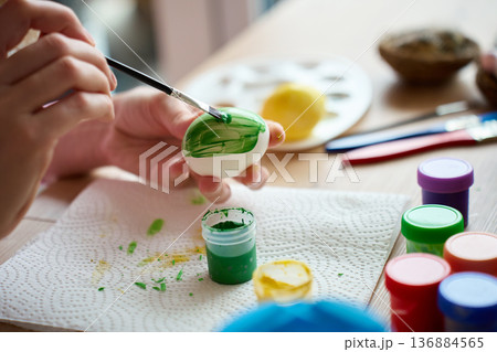 Woman painting Easter egg with green paint and brush Woman painting Easter egg with green paint and brush 136884565