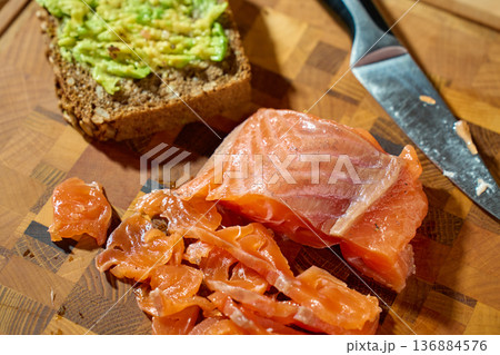 Smoked salmon slices and avocado toast on wooden cutting board 136884576