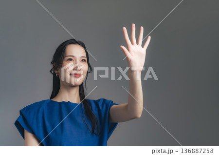空中に手をかざす女性 136887258
