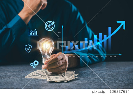 Business leader holding light bulb idea innovation growth concept shows marketing leadership, management knowledge, dollar notes, rising bar graphs, global market growth solution Business leader holding light bulb idea innovation growth concept shows marketing leadership, management knowledge, dollar notes, rising bar graphs, global market growth solution 136887654