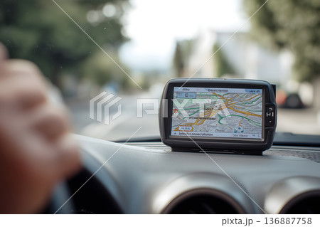 Person is driving a car with a GPS device mounted on the dashboard Person is driving a car with a GPS device mounted on the dashboard 136887758