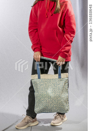 A girl walks with a bag against a gray background. 136888648