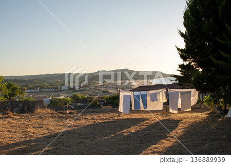 Clothes Hanging on a Line Under the Setting Sun Near the Coast in a Tranquil Landscape With Distant Hills 136889939