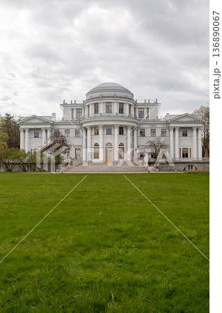 Elegantly Designed White Mansion Surrounded by Green Grass Under a Cloudy Sky in a Serene Setting 136890067