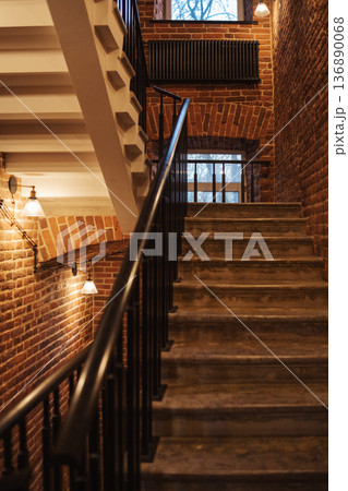 Elegant Staircase With Brick Walls and Warm Lighting in a Cozy Building During the Evening Elegant Staircase With Brick Walls and Warm Lighting in a Cozy Building During the Evening 136890068