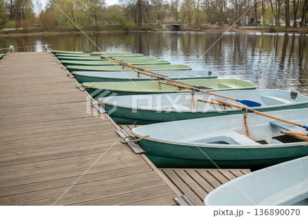 Rowboats Lined on Wooden Dock at Peaceful Lake Surrounded by Trees in Springtime 136890070