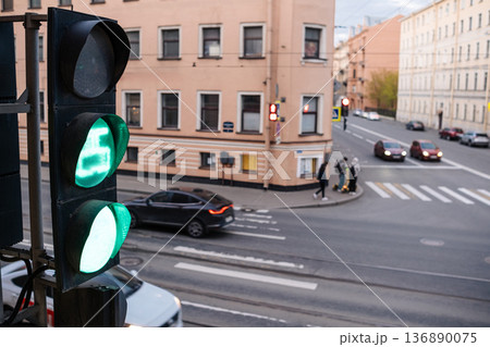 Traffic Light Showing Green at an Urban Intersection During Late Afternoon With Pedestrians and Vehicles in the Vicinity 136890075