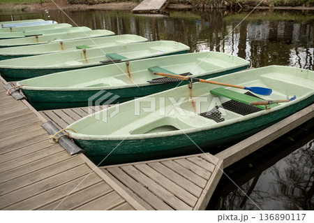 Rowboats Moored at a Wooden Dock by a Peaceful River During Early Spring Afternoon 136890117
