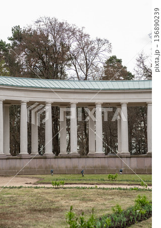 Beautiful Colonnade in a Tranquil Garden Setting With Greenery and Trees in the Background During an Overcast Day 136890239