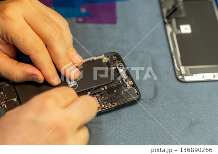 Expert Phone Repair Technician Replacing Battery in a Modern Smartphone at a Workshop 136890266