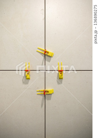 Creative Arrangement of Yellow Clips Securing Tiles in a Neutral-Toned Space During a Bright Day Creative Arrangement of Yellow Clips Securing Tiles in a Neutral-Toned Space During a Bright Day 136890275