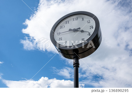 Vintage-style Clock Stands Tall Against a Bright Blue Sky With Fluffy White Clouds During a Sunny Afternoon 136890295