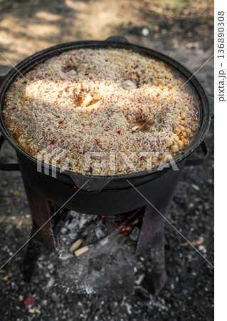 Delicious Rice Dish Cooking in a Traditional Pot Over an Open Fire in a Natural Outdoor Setting 136890308